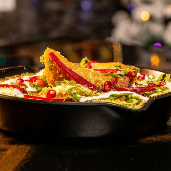Crispy golden tacos in a hot skillet with creamy sauce, herbs, and pomegranate seeds.