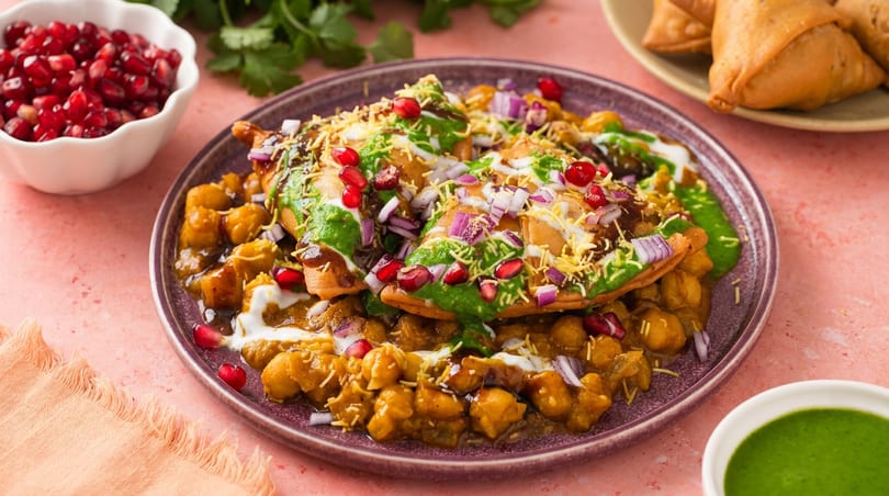 Vibrant Indian chaat with chickpeas, green and tamarind chutneys, pomegranate, and red onions.