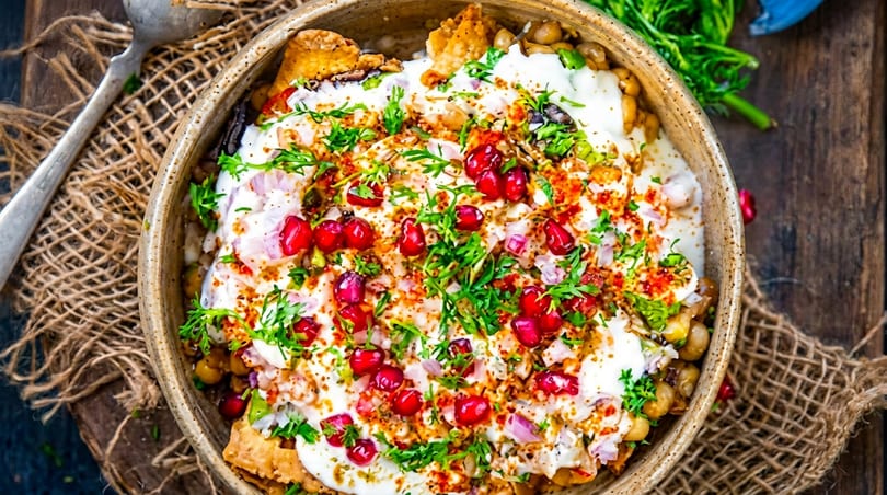 Vibrant Indian chaat with creamy yogurt, red pomegranate seeds, and fresh green cilantro.