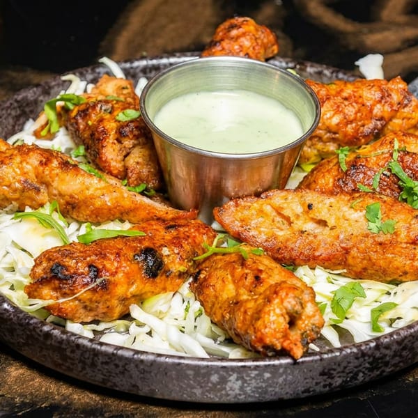 Savory grilled chicken or kebabs served on shredded cabbage with a green dipping sauce.