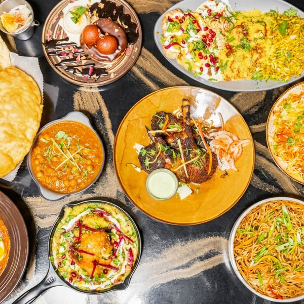 An overhead view of a feast of Indian dishes, including curries, biryani, noodles, and desserts.